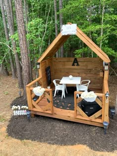 a small wooden structure with white chairs and tables in the middle of some dirt area