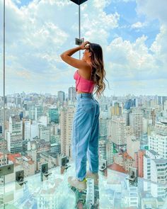 a woman standing on top of a tall building looking at the city from high up