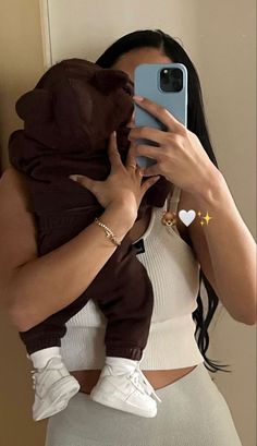 a woman is taking a selfie with her phone while holding a baby in her arms