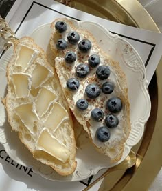 two pieces of bread with blueberries and cheese on them are sitting on a plate