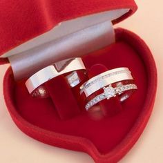 two wedding rings in a heart shaped box with red velvet lining and silver bands on each band