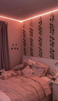 an unmade bed in a bedroom with string lights on the headboard and curtains