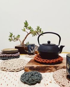 a tea pot on top of a wooden table surrounded by crocheted coasters