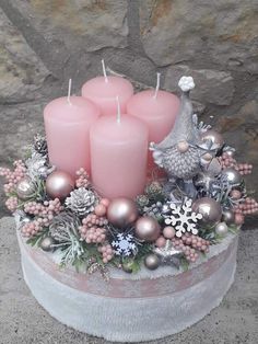 three pink candles sitting on top of a cake covered in ornaments and pineconi