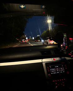 a car driving down a street at night with its lights on and the dash light turned on