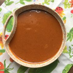 a bowl of soup sitting on top of a table next to a spoon and napkin