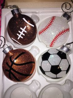 three christmas ornaments in a box with glitter balls and soccer balls on them, one has a football ornament hanging from the top