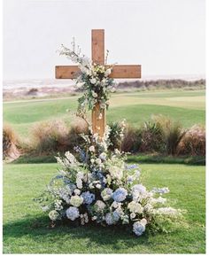 a wooden cross with flowers on the grass