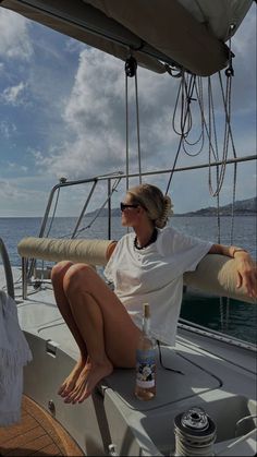 a woman sitting on the back of a boat next to a bottle of booze