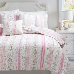 a bed with pink and white bedspread, pillows and pillow cases on it