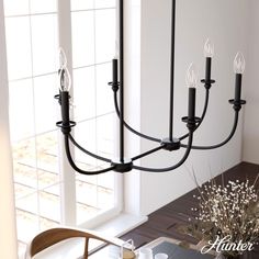 a black chandelier hanging from the ceiling in a dining room with white walls