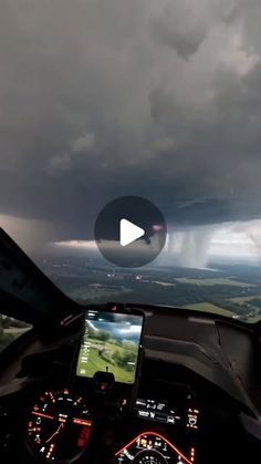 the view from inside an airplane looking down at clouds and rain in the distance, with a cell phone being held up to the camera