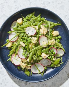 a blue plate topped with peas, radishes and other vegtables