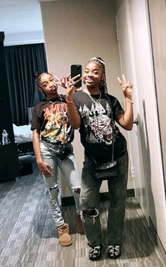 two young women taking a selfie in a hotel room with their cell phones up