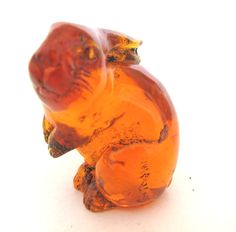 an orange glass animal sitting on top of a white surface