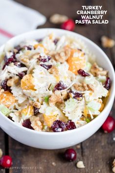 a white bowl filled with fruit and nuts on top of a wooden table next to some cranberries