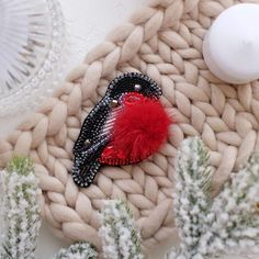 a red and black bird brooch sitting on top of a knitted blanket