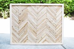 a square wooden frame sitting on top of a cement floor next to trees and bushes