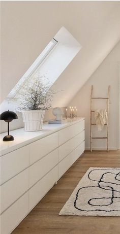 an attic bedroom with white walls and wooden flooring, large rug on the floor