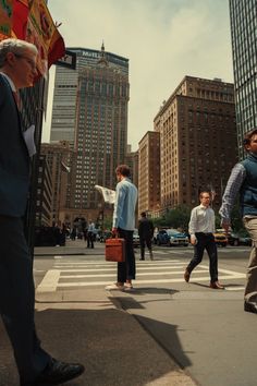 people crossing the street in front of tall buildings