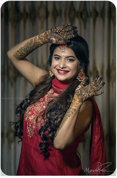 a woman in a red dress with henna tattoos on her arms and hands, smiling at the camera