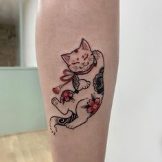 a cat tattoo is on the leg of a woman's legs, with flowers around it