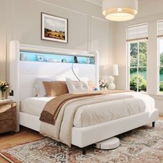 a large white bed sitting in a bedroom on top of a wooden floor next to two windows