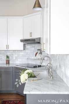 a kitchen with marble counter tops and white cabinets, along with an area rug on the floor