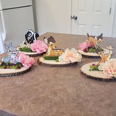 four wooden slices with flowers and animals on them sitting on a kitchen counter next to a refrigerator