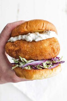 a hand holding a chicken sandwich with lettuce and mayonnaise on it