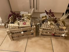 two wooden boxes filled with gifts on top of a tiled floor next to a dishwasher