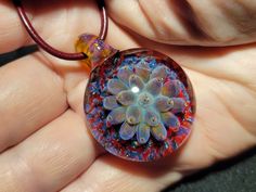 Indulge in the beauty of handcrafted art with these stunning implosion pendants! Each blown glass pendant is meticulously crafted by me, using only the finest quality Borosilicate glass and a blowtorch in my studio. I take great pride in the intricate designs and depth of each pendant, which remind me of the delicate lotus blossoms, succulents or anemones, carefully captured in glass. As a one-of-a-kind creation, each pendant is truly unique and crafted entirely from molten glass.  The pendant has a large glass bail  which also provides flexibility to change the chains and cords for a different look. The pendant comes with a leather cord with a sterling silver lobster claw clasp. I custom-make each leather cord to order and can accommodate different lengths as per your request. I take grea Unique Handmade Orb Jewelry, Handmade Glass Pendant Jewelry, Handmade Spiritual Murano Glass Jewelry, Unique Glass Pendant Jewelry, Unique Iridescent Round Pendant Jewelry, Clear Glass Round Pendant Jewelry, Handmade Round Jewelry From Recycled Glass, Unique Handmade Clear Jewelry, Handmade Clear Round Pendant Jewelry