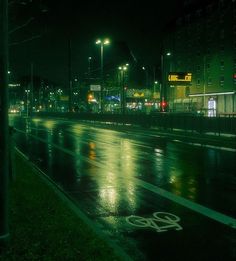 an empty city street at night with rain on the ground and buildings in the background