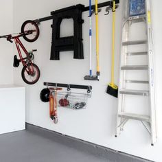 there is a bike hanging on the wall next to a bicycle rack and ladders