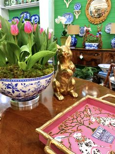 a wooden table topped with a vase filled with flowers and a bunny figurine