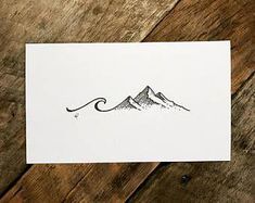 a piece of paper with a drawing of a mountain on it sitting on top of a wooden table