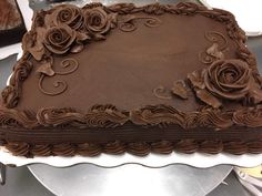 a large chocolate cake sitting on top of a white plate covered in frosting roses