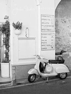 a scooter parked in front of a building next to a sidewalk with potted plants