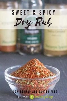 a glass bowl filled with dry rubs next to two bottles of spices on a table