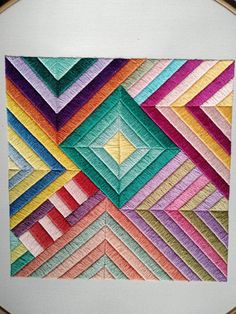 a close up of a piece of art made out of different colored paper squares and triangles