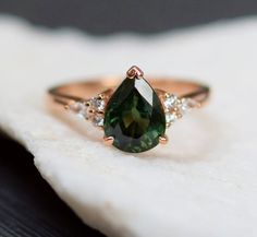 a close up of a ring with a green and white stone in the center on a piece of cloth