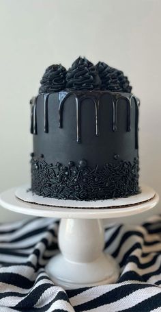 a black and white striped table cloth with a cake on it, covered in chocolate icing