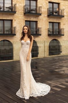 a woman in a wedding dress standing on a wooden floor outside an apartment building with balconies