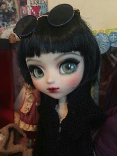 a close up of a doll with sunglasses on it's head and black hair