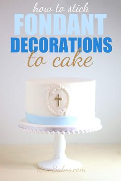 a white cake with blue icing and a cross on the top that says how to stick fondant decorations to cake