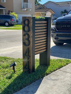 a large wooden sign sitting on the side of a road next to a parking lot