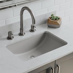 a white sink sitting on top of a counter next to a wooden box with succulents