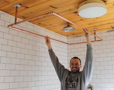 a man is standing in the shower with his arms up and hands on the ceiling