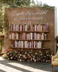 a book shelf filled with lots of books next to a wall covered in flowers and greenery