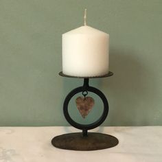 a white candle sitting on top of a metal stand with a heart in the middle